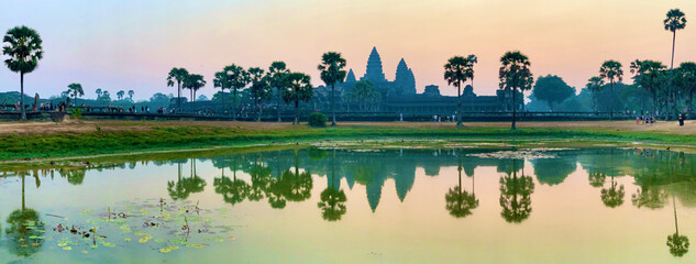 Obraz premium Siem Reap, Cambodia - February 20, 2020: Wide Panoramic View of Angkor Wat Temple and Its Reflection in a Lily Pad Pond at Sunset