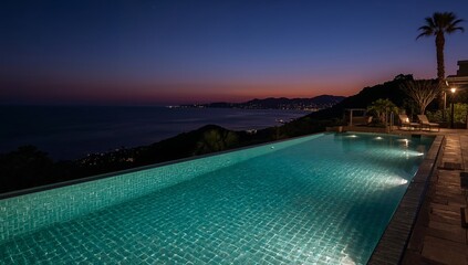 Fototapeta premium Beautiful Night View of a Pool Overlooking the Ocean With Lights Reflecting on the Water