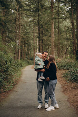 Obraz premium A warm family walk along a forest path. Parents are spending time with their child amidst tall trees and nature.