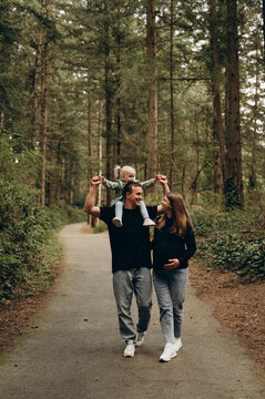 A warm family walk along a forest path. Parents are spending time with their child amidst tall trees and nature.