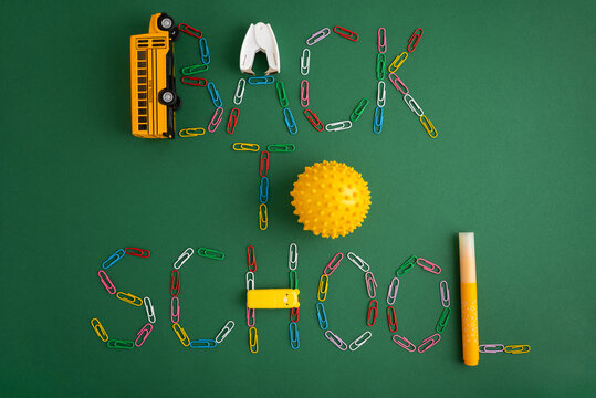 Back to school lettering with stationery items on green background