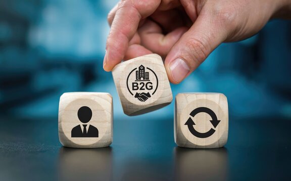 Hand placing a wooden cube with b2 g business and handshake symbol