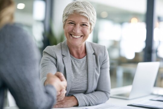 Happy senior businesswoman shaking hands in office meeting