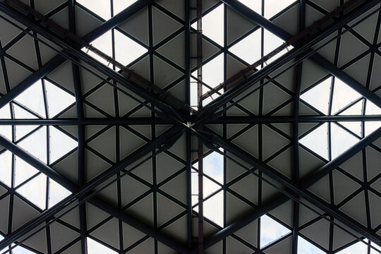 Symmetrical low angle view of modern geometric steel and glass roof framework abstract architectural background