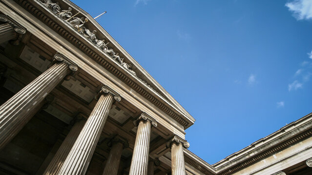 Classical Pillars Of The British Museum. Low angle view of famous historic London landmark under a clear blue sky.