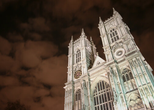 Westminster Abbey Facade. Low angle view of the famous Gothic church in London illuminated against a cloudy night sky