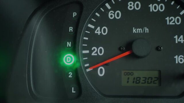 Close-up of an automatic transmission gear indicator switching between modes on a car dashboard. Vehicle controls, driving, automotive technology, and transportation concept.