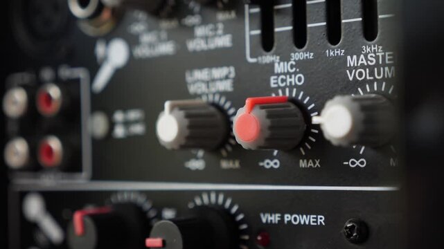 Hand adjusting microphone echo knob on an audio mixer console