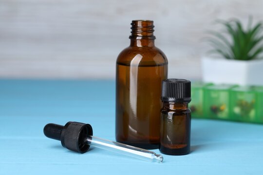 Bottles with medical products, dropper and pills on blue wooden table, selective focus. Space for text