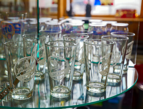 DULUTH, MN - 24 JUN 2026: Leinenkugel's Brewing Company 150th anniversary pint glasses on glass display stand in antique collectibles store, Duluth, Minnesota.