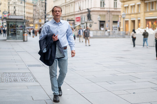 55 Year Old Man Walking Along Vienna Street Holding Jacket