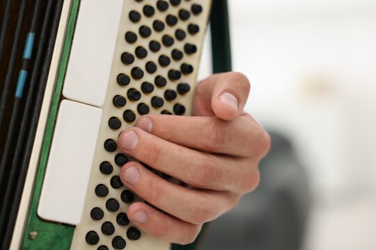 Man playing piano accordion at home, closeup. Space for text