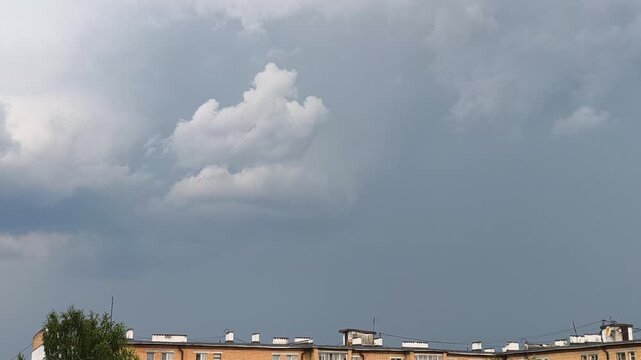 A brief lightning discharge against dense storm clouds above an urban neighborhood. High-quality atmospheric footage of severe weather. Storm Clouds and Lightning Strike Above the City.