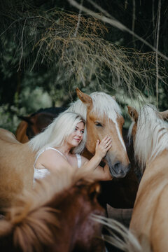 A woman with white hair next to a horse with a white mane. Concept of hair strength and health.