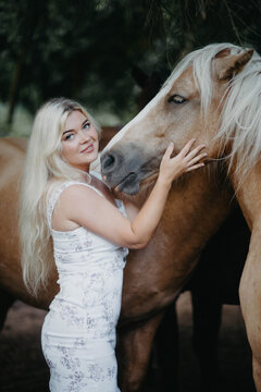 A woman with white hair next to a horse with a white mane. Concept of hair strength and health.