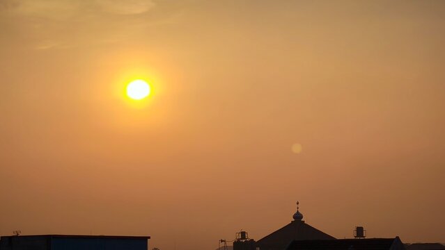 A serene mosque silhouette at sunset with a vibrant yellow sun