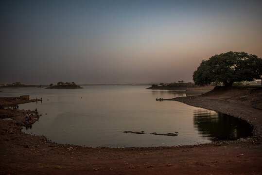 Gaurishankar Lake in Bhavnagar during sunset with a large tree.