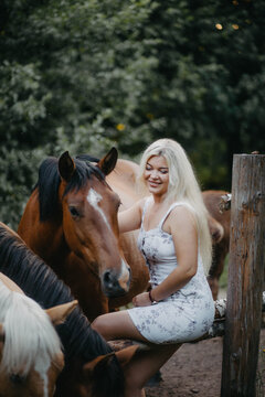 Blonde woman with horses in the garden in summer