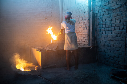 Indian worker standing next to a blazing furnace in a foundry