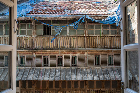 Facade of an ancient wooden building in Mumbai seen through a window