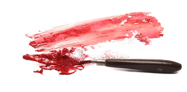 Metal spatula and red brush strokes oil paint isolated on white background, side view