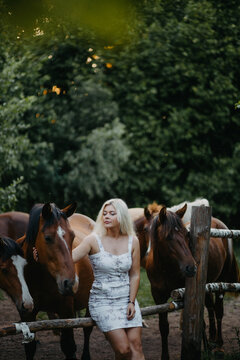 A blonde woman is walking with a horse on a ranch