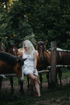 A blonde woman is walking with a horse on a ranch