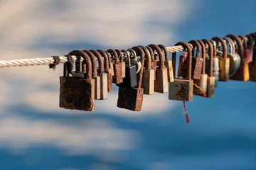 Rusted Love Locks Hanging on Metal Cable by Blue Water © Viviana