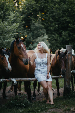 A blonde woman is walking with a horse on a ranch