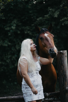 Blonde woman with horses in the garden in summer