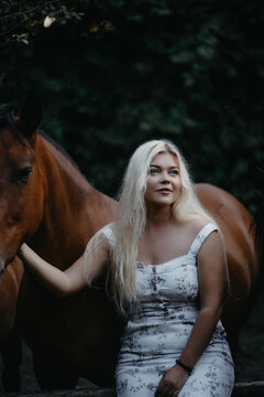 Blonde woman with horses in the garden in summer