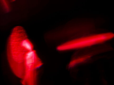Abstract red light leaks with glowing red light streaks against dark background. Visual effect created by camera movement or light trails. Graphic background for design.