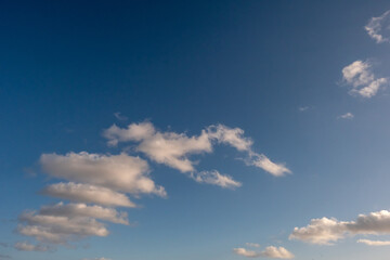 Fototapeta premium Blue sky with interesting clouds, one resembles letter M. Nature background for design.