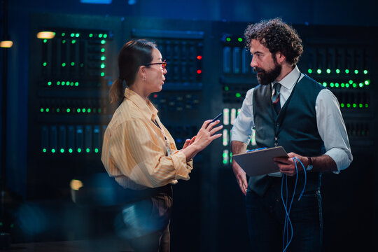 It specialists collaborating on network solutions in a data center, discussing server maintenance and cybersecurity