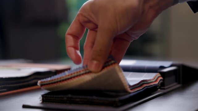 closeup of hands feeling and selecting different quality fabrics from a fabric book