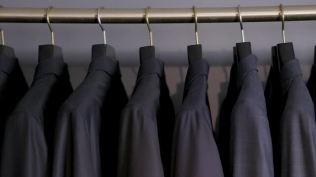 multiple suits on hangers in a closet