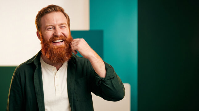 Man with red beard smiling and touching his hair in colorful background  