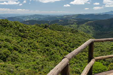Fototapeta premium Scenic viewpoint at Chapéu do Bispo hiking trail over lush Atlantic Forest and rolling mountains under summer morning sunny clear blue sky horizon in Monte Verde, Camanducaia, Minas Gerais - Brazil