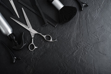 Naklejka premium Professional hairdresser tools on a black textured concrete background.