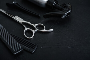 Professional hairdresser tools on a black textured concrete background.