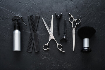 Fototapeta premium Professional hairdresser tools on a black textured concrete background.