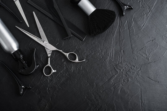 Professional hairdresser tools on a black textured concrete background.
