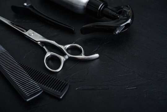 Professional hairdresser tools on a black textured concrete background.