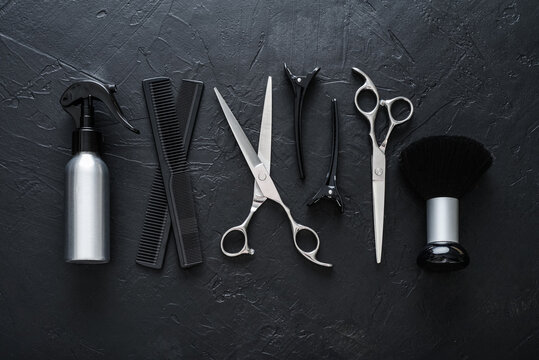 Professional hairdresser tools on a black textured concrete background.