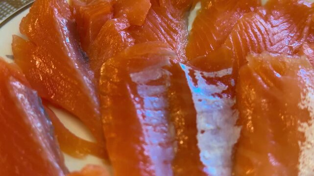 Red salmon strips on plate, festive table closeup showing glossy texture, delicate salt sprinkle, thin slices arranged in fan