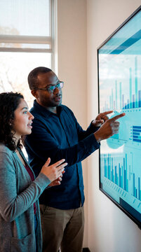 Two colleagues analyzing research data on a large screen in a laboratory office