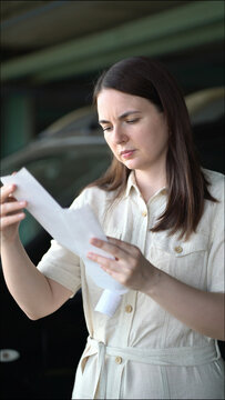 Worried woman examines a long paper receipt with concerned expression, showing financial stress, money worries and budget problems.