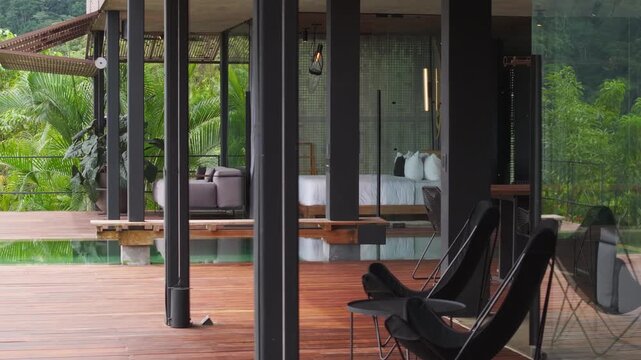 Villa in Costa Rica features modern architecture with open-air bedroom and wooden deck terrace. Private pool reflects lush tropical rainforest surrounding the elegant resort accommodation.
