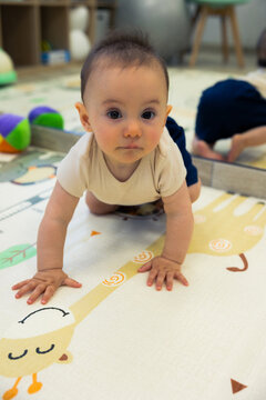 Baby crawling looking at camera on play mat