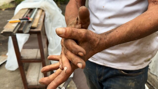 Close up of male dirty hands of adult labor at construction. Repairman rubbing unclean arms after hard work at the site. Concept of exhausting and hard work. Slow motion
